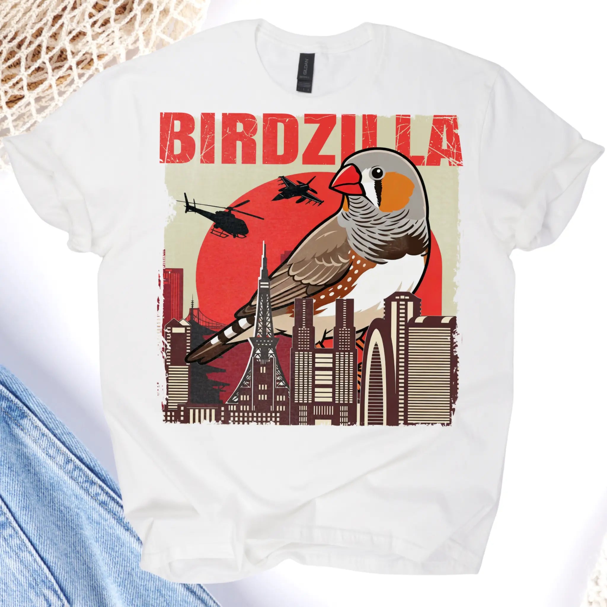 White t-shirt with a graphic design of a bird, cityscape, and helicopter on a white background